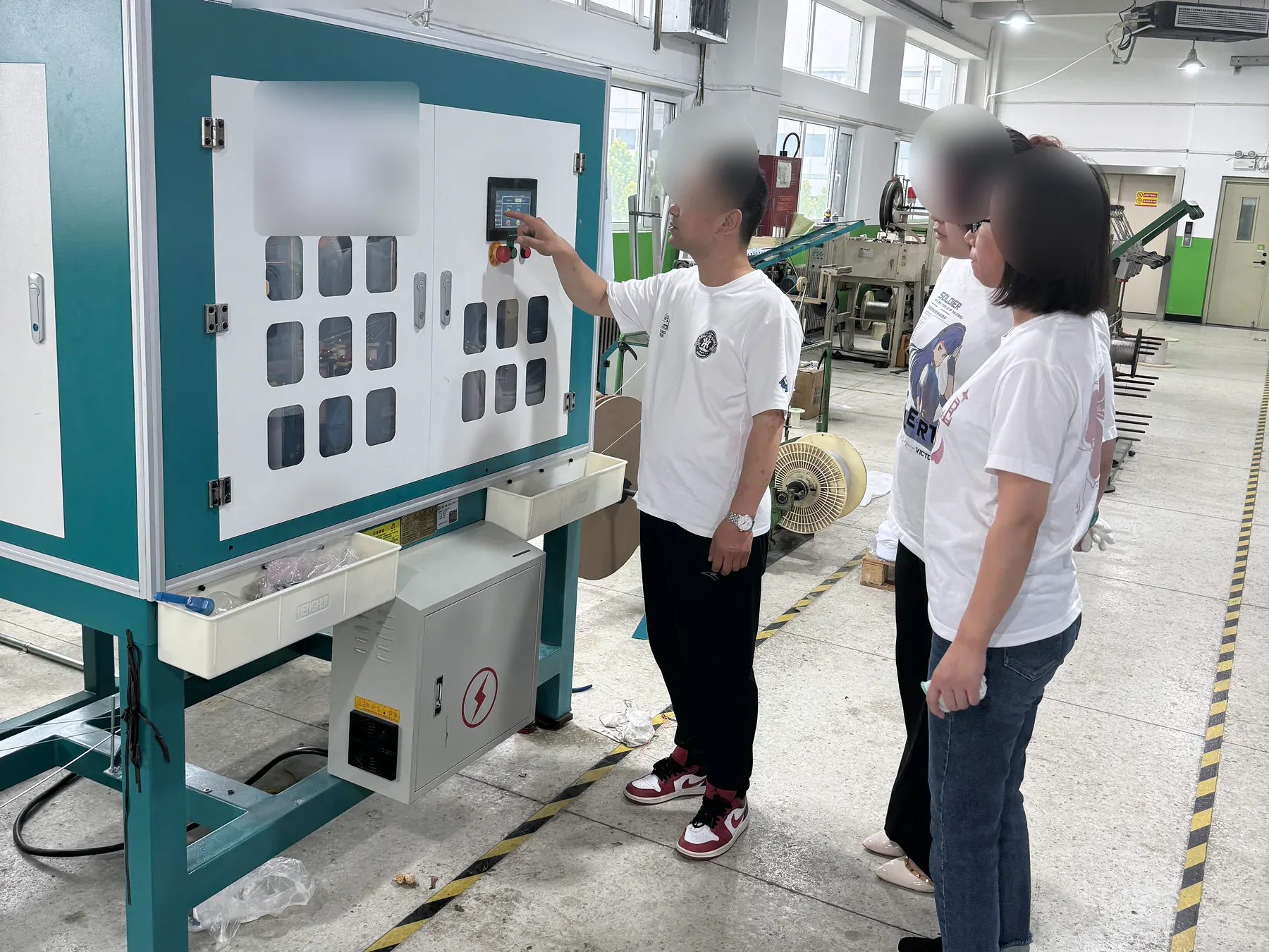 Two staff members reviewing an equipment control panel inside the MTTJ Tianjin workshop
